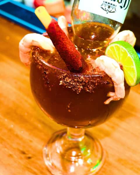 Shrimp cocktail in tomato-based sauce with avocado and lime, garnished with shrimp and served with saltine crackers.