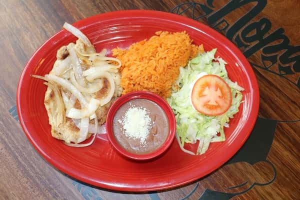 Grilled pork chop topped with sautéed onions, served with Mexican rice, shredded lettuce, tomato, and refried beans.