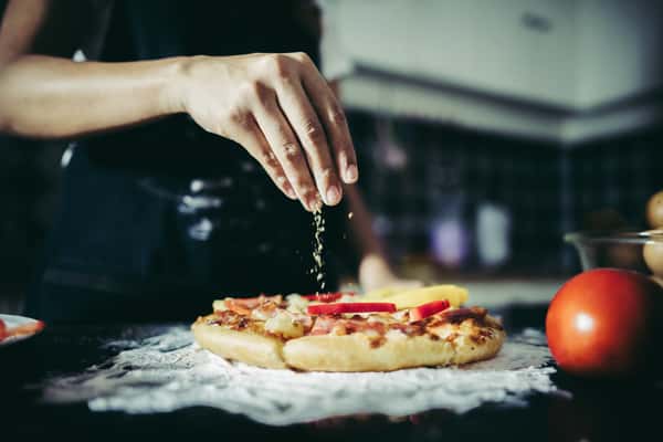 pizza chef sprinkling cheese on pizza