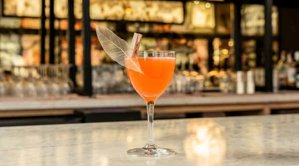 orange-cocktail-drink in a coupe glass on a marble bar