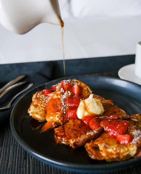 Syrup being poured on a plate of french toast