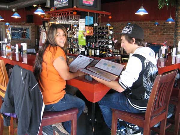 two cutomers sitting at the bar looking at a menu