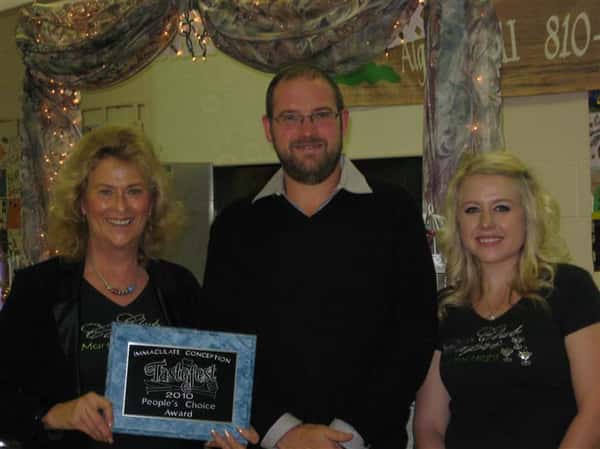three employees posing for picture. one is holding a plaque
