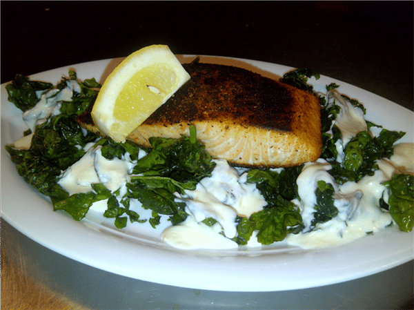 grilled salmon over pasta noodles with a lemon wedge