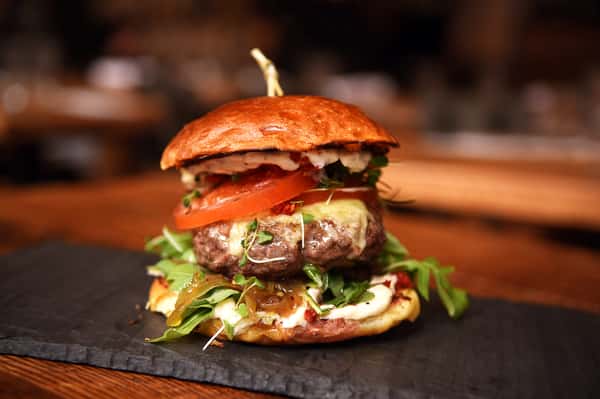 Juicy gourmet hamburger stacked with fresh lettuce, tomato, and melted cheese, served with crispy fries on the side.