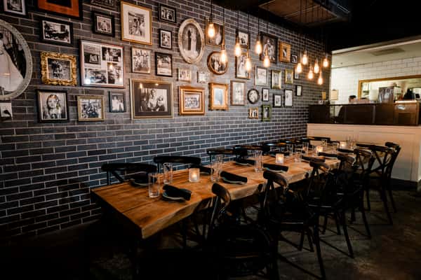 Dining table with chairs in front of a wall full of picture frames
