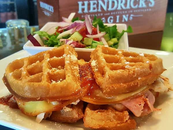 egg sandwich between waffles with a side salad