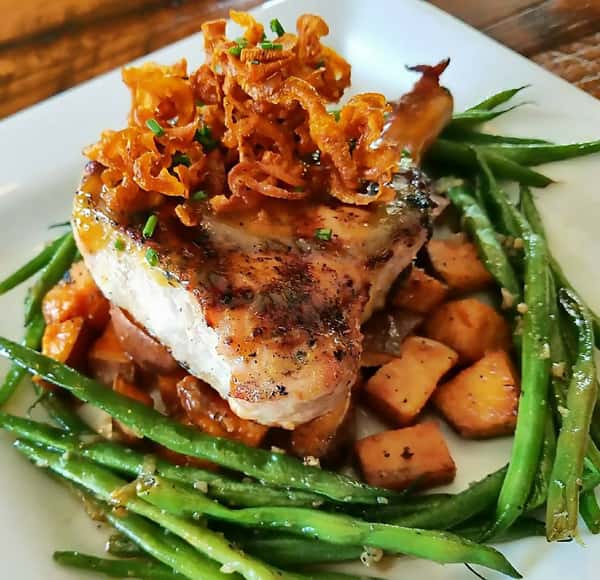 cooked fish over potatoes with crispy onions and asparagus