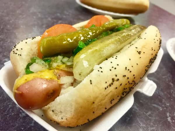 Classic Chicago-style hot dog topped with mustard, relish, onion, tomato, pickle spear, and sport peppers in a poppy seed bun.