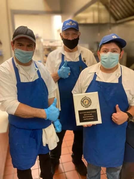 Three staff members from Pappa Gyros proudly pose in their kitchen uniforms, with one holding an award plaque that reads "Katy/Fort Bend Foodies Best of 2023 Mediterranean – Pappa Gyros."