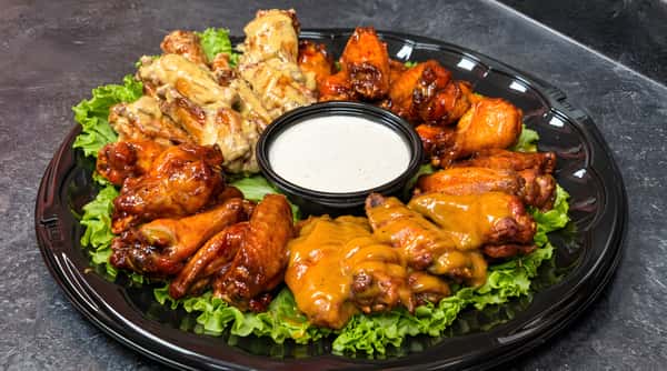 Chicken wing platter with various sauces (honey mustard, BBQ, buffalo), arranged on lettuce with a ranch dip in the center.
