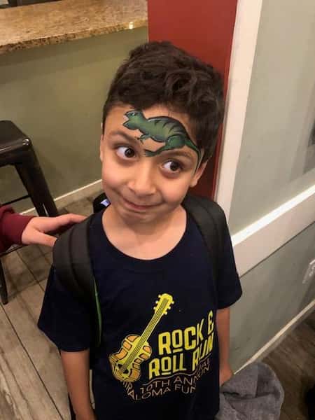 child with face painting of a dinosaur