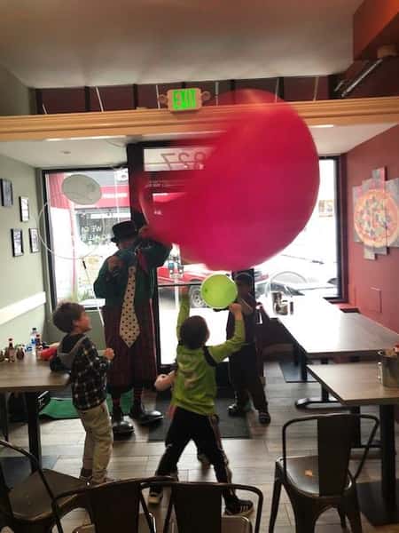 children playing with a clown and balloons