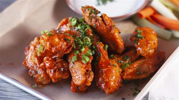 traditional buffalo wings in a basket with ranch dipping sauce