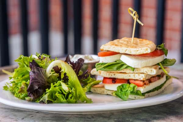Photo of the Caprese Sandwich, plated with a side of mixed greens.