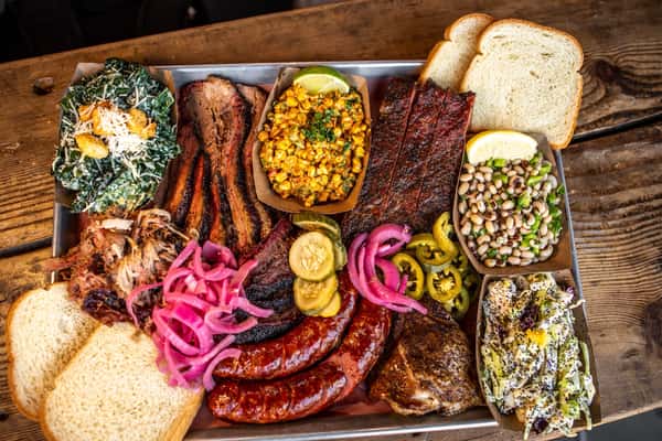 Texas-style BBQ tray with brisket, beef ribs, sausage and house pickles at Outsider BBQ, Seattle
