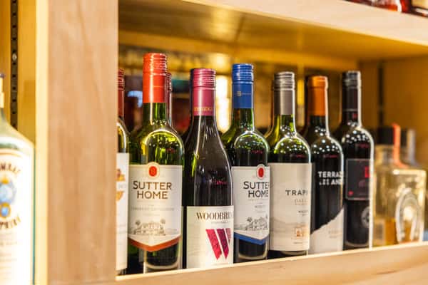 Assorted red and white wine bottles displayed on wooden shelves at Tijuana Joe's Mexican restaurant bar.