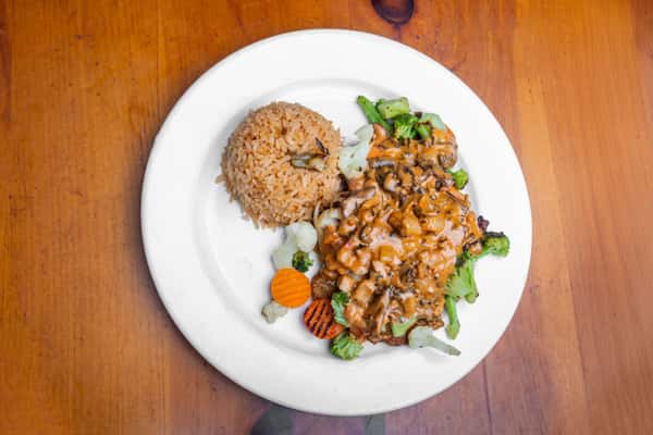 Grilled chicken breast topped with savory mushroom cream sauce, served with Mexican rice and steamed vegetables, presenting a hearty Tex-Mex dinner entrée with rich flavors and fresh ingredients.