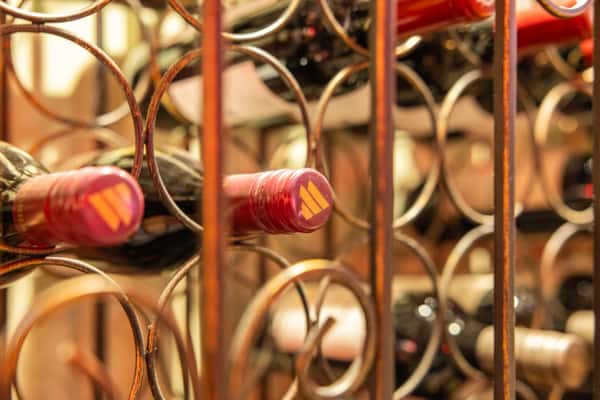 Assorted red wine bottles displayed in a decorative metal wine rack, highlighting the curated wine selection at a cozy Mexican bar and grill.