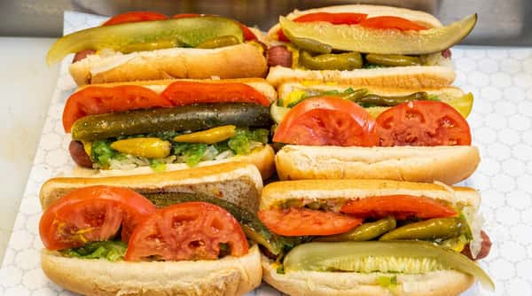 Chicago-style hot dogs with pickles, tomatoes, relish, and yellow peppers.