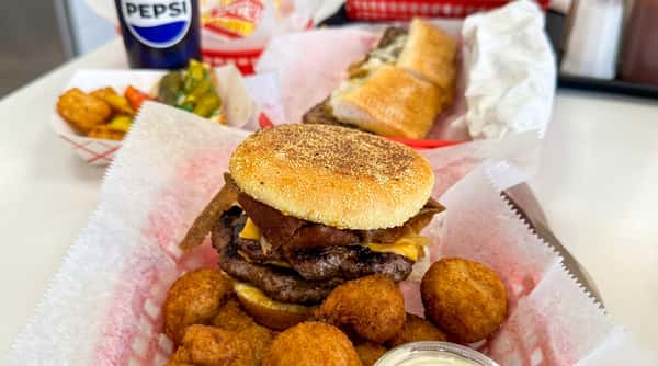 Double patty cheeseburger with bacon, served with fried hushpuppies, a sandwich, and a drink.