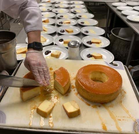 Cheese cake on cutting board with dozens of plates in the background