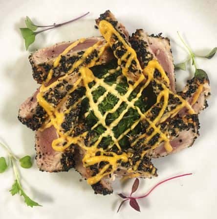 Seared tuna with black sesame seeds with yellow sauce drizzle