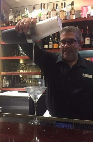 Bartender pouring martini in martini glass