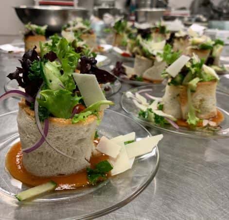 Catering dishes with bread wrapped around lettuce on glass plate
