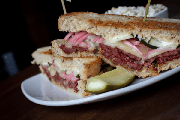 Pastime sandwich cut in half with a side of coleslaw and a pickle
