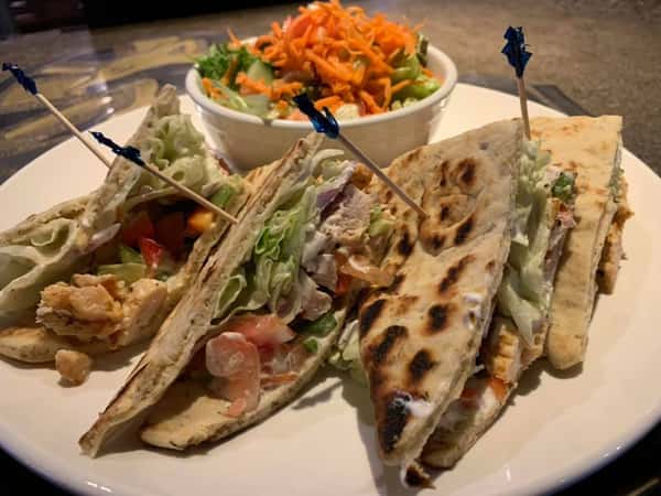 four folded tortillas with chicekn, lettuce and tomato in it, a side of coleslaw
