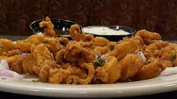 calamari with two sauces in black cups. a white sauce and a brown sauce
