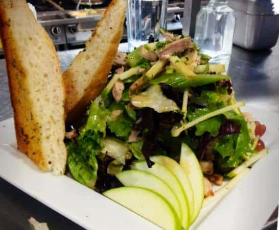a salad with lettuce onions and green apples. two pieces of bread
