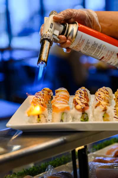 chef applying torch to sushi rolls