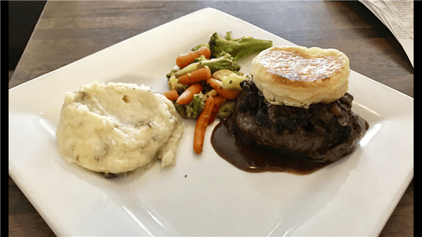 steak, mashed potatoes, puff pastry, and assorted veggies on a plate