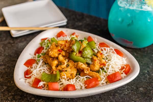 Crispy noodles topped with sweet chili chicken, green bell peppers, and diced tomatoes, served in a triangular bowl.