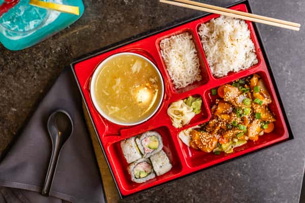 Japanese bento box with teriyaki chicken, California rolls, steamed rice, egg drop soup, wasabi, and pickled ginger.