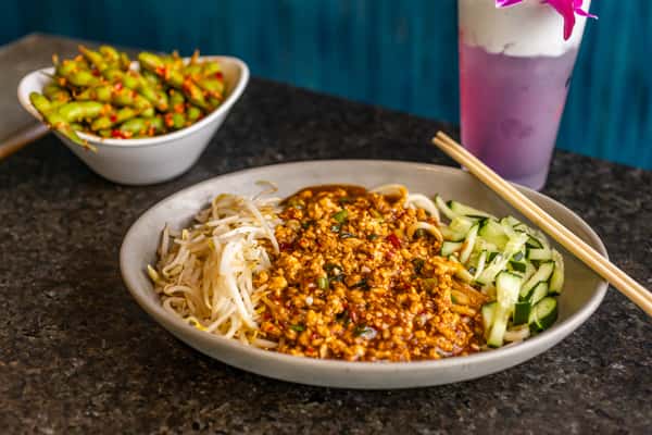 Spicy ground chicken over noodles with bean sprouts and cucumber, served with chili garlic edamame and a purple coconut drink.