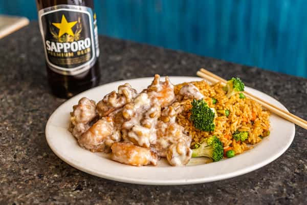 Creamy walnut shrimp served with fried rice, broccoli, and vegetables, paired with a bottle of Sapporo beer.