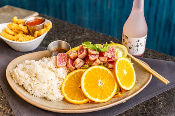 Seared ahi tuna with white rice, fresh orange slices, and dipping sauce, served with crispy calamari and a bottle of Sayuri sake.