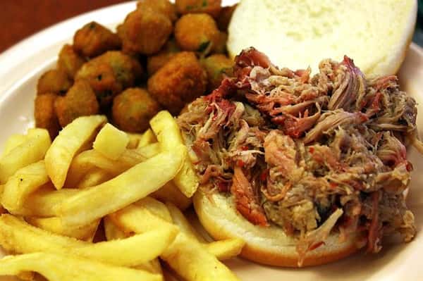 pulled pork in a roll with a side of fries