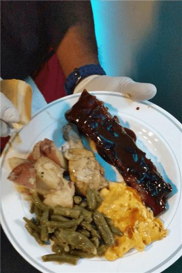 chef holding a plate full of bbq ribs and vegetables