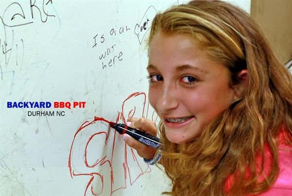 young woman drawing on the walls of backyard bbq pit