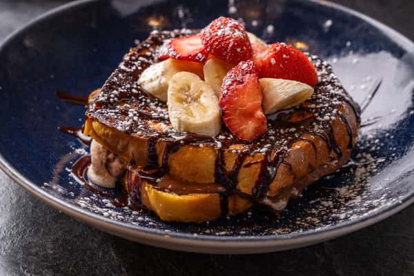 French toast with chocolate syrup, bananas and strawberries