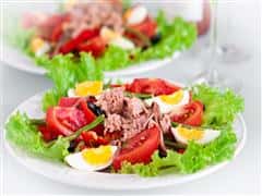 Lettuce, Corn beef, sliced boiled eggs, over greens on a plate.