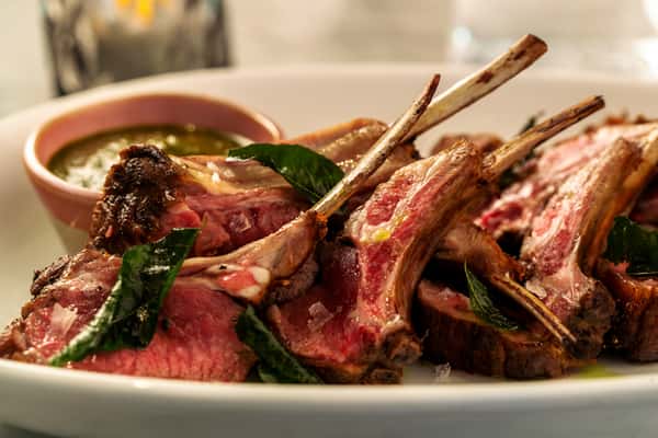 Grilled lamb chops served medium rare with roasted vegetables and a lifted bone-in chop for presentation.