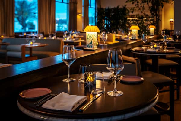 Elegant restaurant dining room with candlelit tables, wine glasses, and warm ambient lighting.