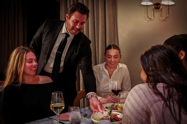 Restaurant server presenting a beautifully plated meal to guests enjoying a refined dining experience.