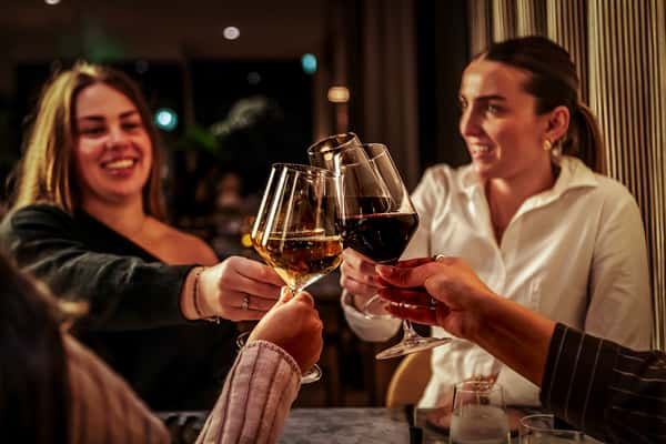 Guests raising wine glasses in a toast during an elegant dining experience at an upscale restaurant.
