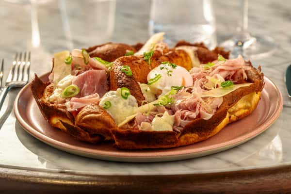 Crispy flatbread topped with prosciutto, soft-cooked egg, fresh herbs, and shaved cheese.